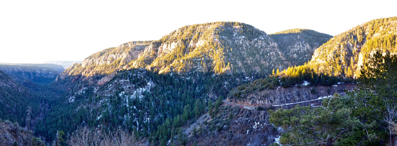 Sunrise panorama over Oak Creek Canyon, red rock walls rising above the forested canyon floor